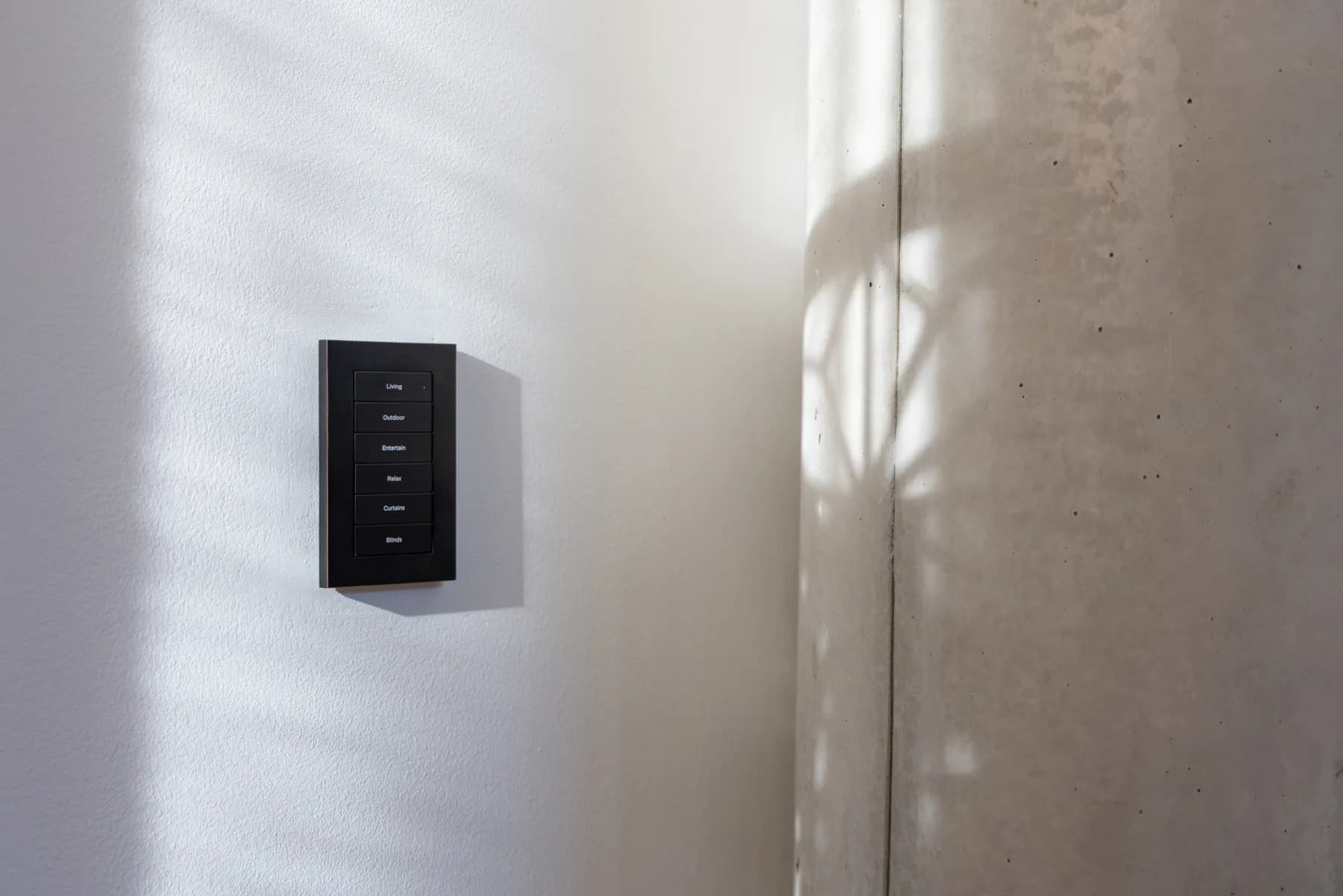 Black Control4 lighting keypad on a pale wall